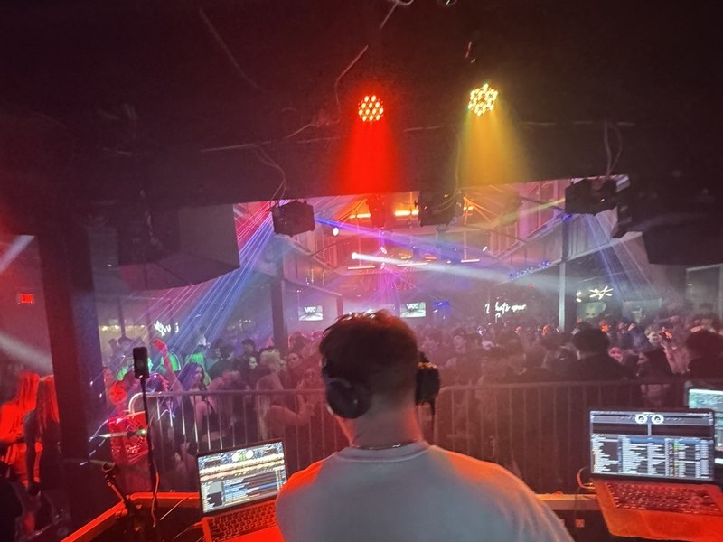 VATO DJing a packed nightlife crowd with stage lighting